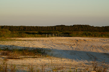 Image showing end of dirt road blocked by gate at sunset