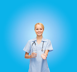 Image showing smiling doctor or nurse offering pills and water