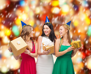 Image showing three smiling women in blue hats with gift boxes