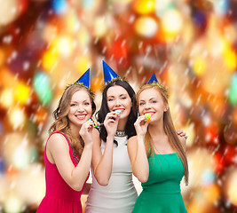 Image showing three smiling women in hats blowing favor horns