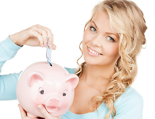 Image showing woman puts cash money into big piggy bank