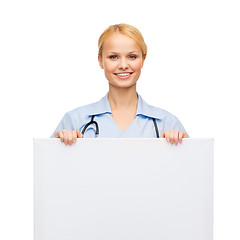 Image showing smiling female doctor or nurse with blank board