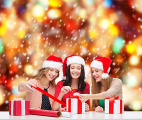 Image showing smiling women in santa helper hats with gift boxes