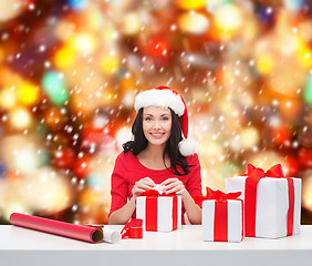 Image showing woman in santa helper hat with many gift boxes