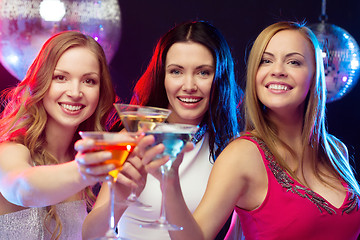 Image showing three smiling women with cocktails and disco ball