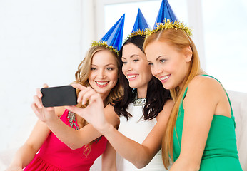 Image showing three smiling women in hats having fun with camera