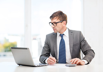 Image showing businessman with computer, papers and calculator