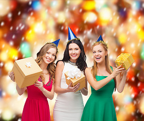 Image showing three smiling women in blue hats with gift boxes