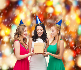 Image showing three smiling women in blue hats with gift box