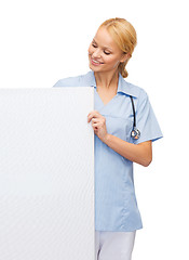 Image showing smiling female doctor or nurse with blank board