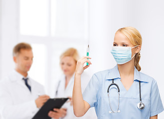 Image showing female doctor or nurse in mask holding syringe