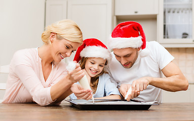 Image showing happy family in santa helper hats making cookies