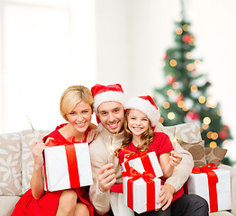 Image showing smiling family holding gift boxes and sparkles