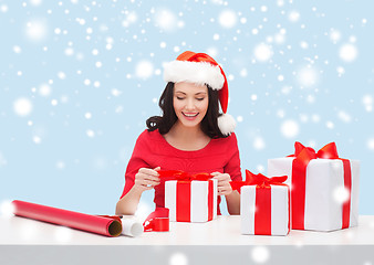 Image showing woman in santa helper hat with many gift boxes