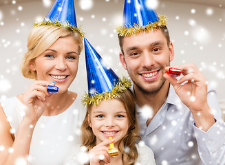 Image showing smiling family in blue hats blowing favor horns