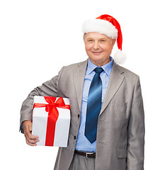 Image showing smiling man in suit and santa helper hat with gift