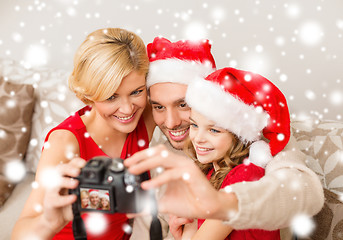 Image showing smiling family in santa helper hats taking picture