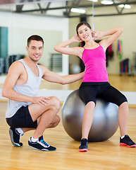 Image showing male trainer with woman doing crunches on the ball