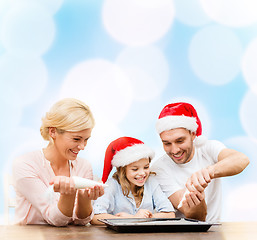 Image showing happy family in santa helper hats making cookies