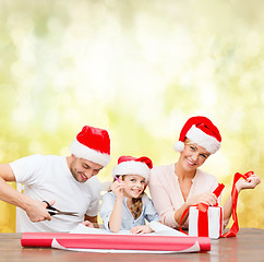 Image showing smiling family in santa helper hats with gift box