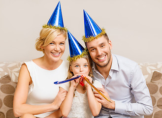 Image showing smiling family in blue hats blowing favor horns