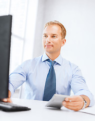 Image showing businessman with calculator, computer and papers