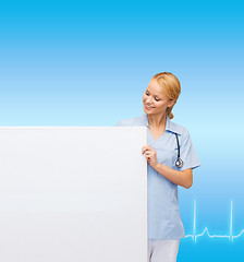 Image showing smiling female doctor or nurse with blank board