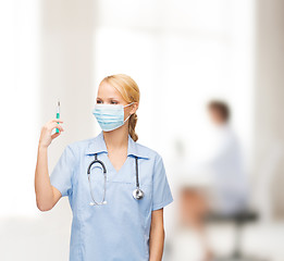 Image showing female doctor or nurse in mask holding syringe