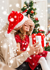 Image showing smiling father surprises daughter with gift box