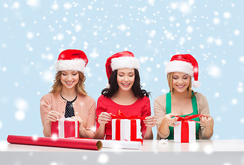 Image showing smiling women in santa helper hats with gift boxes