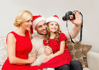 Image showing smiling family in santa helper hats taking picture