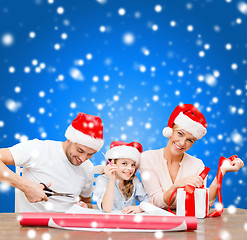 Image showing smiling family in santa helper hats with gift box