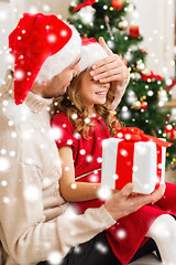 Image showing smiling father surprises daughter with gift box