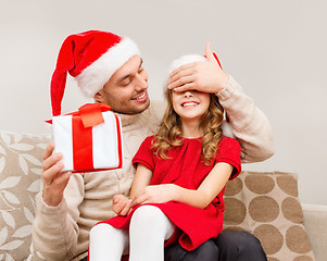 Image showing smiling father surprises daughter with gift box