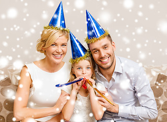 Image showing smiling family in blue hats blowing favor horns