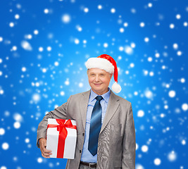 Image showing smiling man in suit and santa helper hat with gift