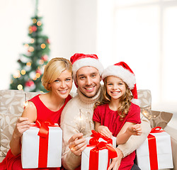 Image showing smiling family holding gift boxes and sparkles