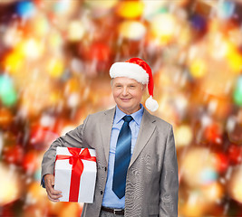 Image showing smiling man in suit and santa helper hat with gift