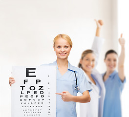 Image showing smiling female doctor or nurse with eye chart