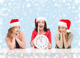 Image showing women in santa helper hats with clock showing 12