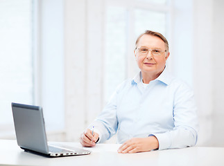 Image showing old man in eyeglasses filling a form at home