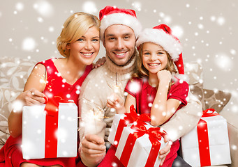 Image showing smiling family holding gift boxes and sparkles