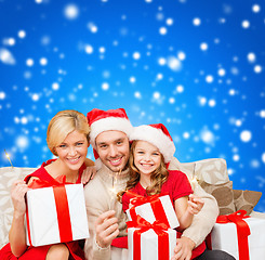 Image showing smiling family holding gift boxes and sparkles