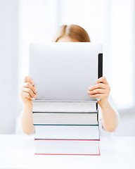 Image showing girl hiding behind tablet pc and books at school