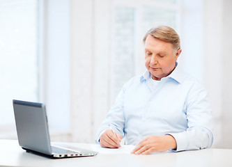 Image showing old man filling a form at home