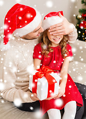 Image showing smiling father surprises daughter with gift box