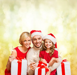 Image showing smiling family holding gift boxes and sparkles