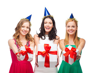 Image showing three smiling women in blue hats with gift boxes