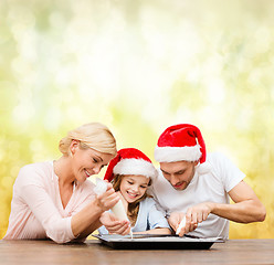 Image showing happy family in santa helper hats making cookies