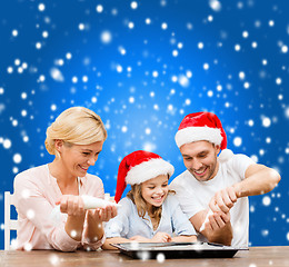 Image showing happy family in santa helper hats making cookies